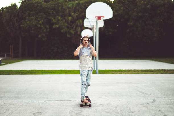 Handsome hipster type guy skateboarding on a basketball court