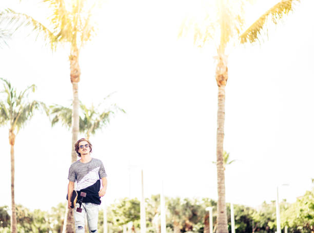 istock Handsome guy with skateboard and palm trees 1269989919
