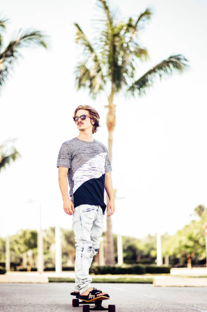 istock Cool guy skateboarding with sunglasses in tropical place 1269989944