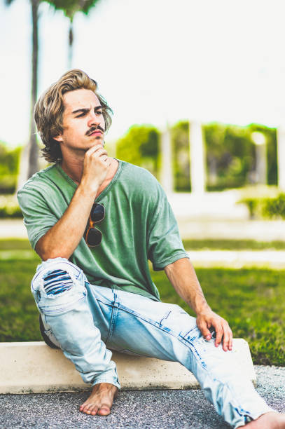istock Barefoot young man sits on a curb outside 1269990813