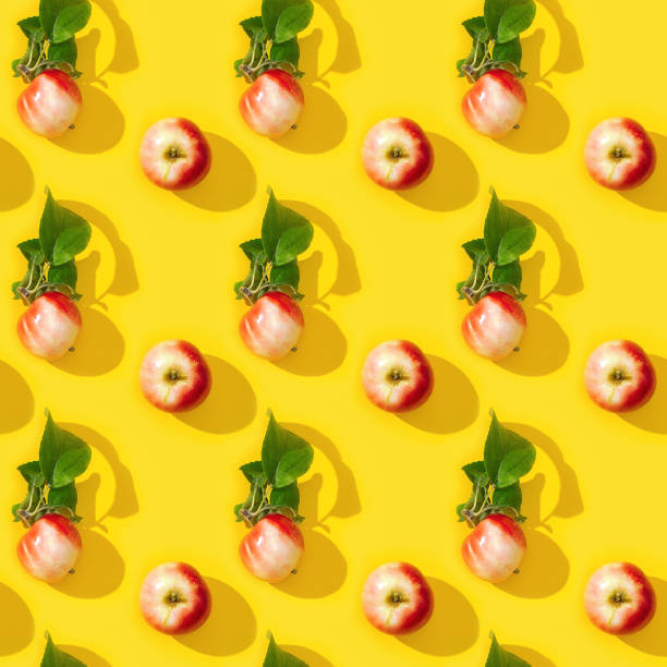 istock Seamless regular creative pattern from small red apples and green leaves with dark shadows. 1269992428