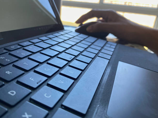istock Hand operates a mouse in the background with laptop keyboard in the foreground 1269993805