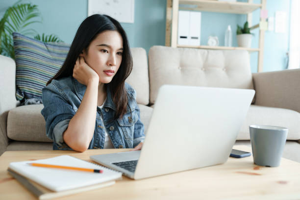 istock working from home. beautiful of young woman using computer laptop while sitting on the floor in the living room in the morning at house 1269994439