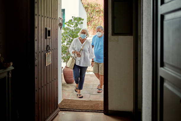 istock Senior Couple Returning Home Wearing Protective Face Masks 1269997064
