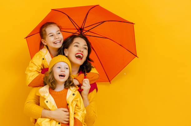 Family with umbrella on colored background.