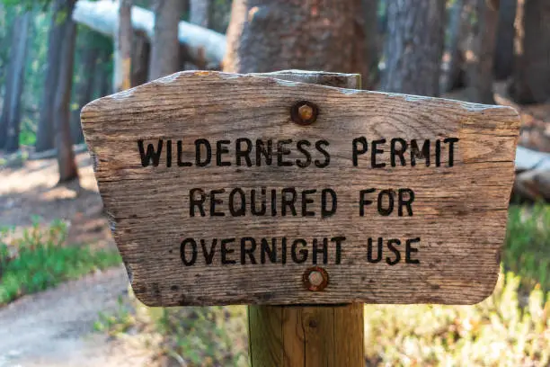 Wilderness permit required for overnight use sign on the wooden post in the national forest.