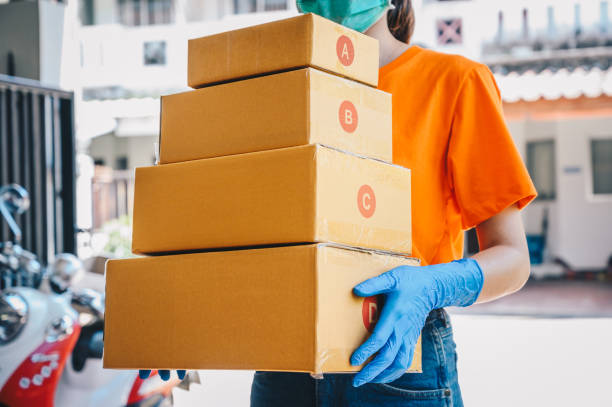istock Delivery service courier holding boxes mail for sending to customer while wearing mask and glove for protect herself in covid-19 pandemic outbreak. 1269998664