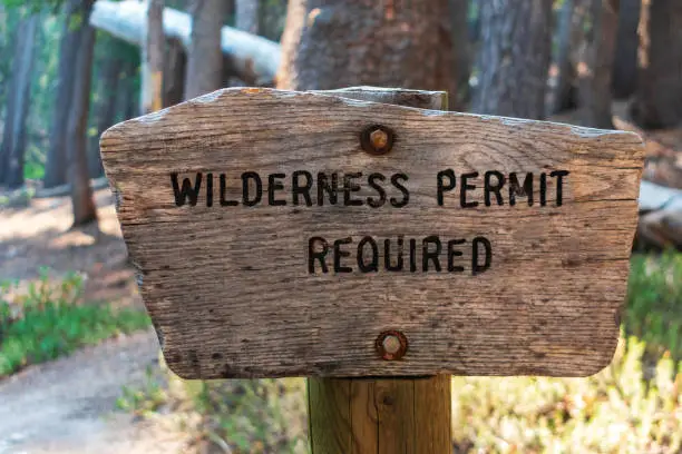 Wilderness permit required sign on the wooden post in the national forest.