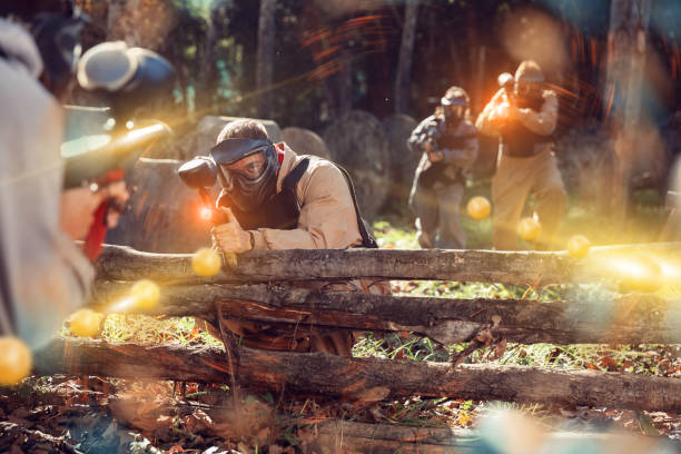 Men and women playing paintball Men and women in protective uniform playing paintball on shooting range paintball photography stock pictures, royalty-free photos & images