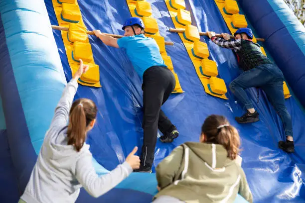 Photo of Friends climbing on inflatable slide in amusement park