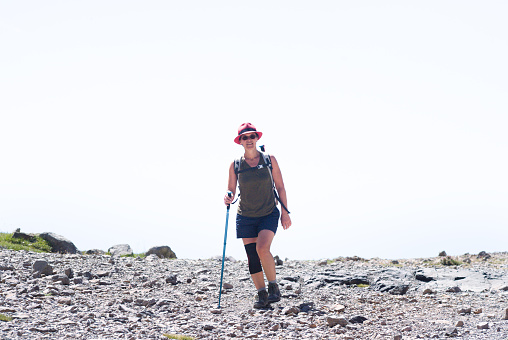 A lone female hiker climbing cobbled steps on Pendle Hill near Clitheroe in Lancashire, England stops for a rest.