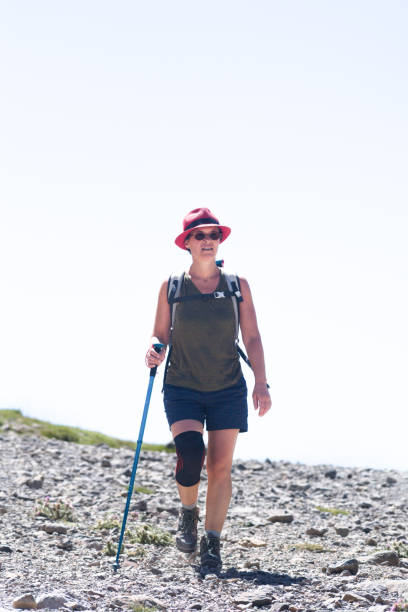 istock A woman walks down a stony slope with a kneepad and a stick and a red hat 1270007424