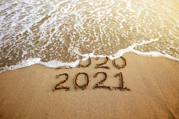 New year 2021 and 2020 on sandy beach with waves