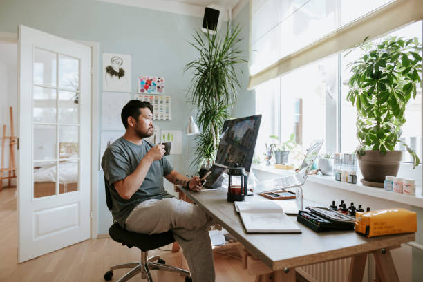 digital artist contemplates during coffee break in his home office - home office imagens e fotografias de stock