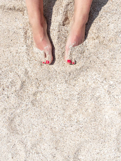 vista dall'alto delle gambe femminili con pedicure rossa nella sabbia della spiaggia. riposo e ricreazione in mare. copiare lo spazio. - human foot barefoot sole of foot human toe foto e immagini stock