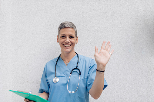 Studio portrait of a mid adult female doctor in uniform waving.
