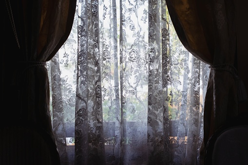 Handmade lace curtains in a dark room.