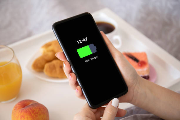 istock female hands holding phone with charged battery on the screen 1270025311