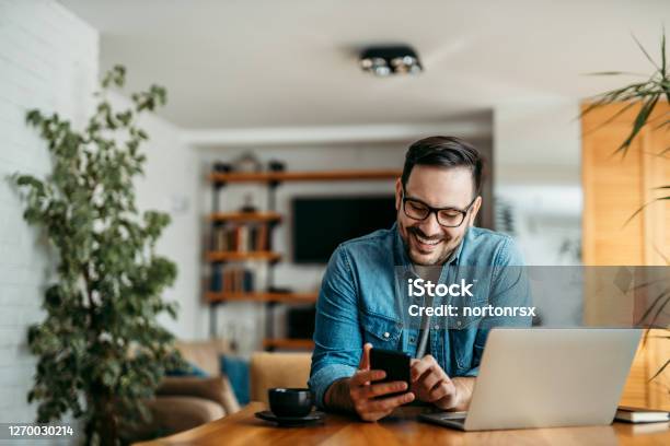 Portrait Of A Cheerful Man Using Smart Phone At Home Office Stock Photo - Download Image Now