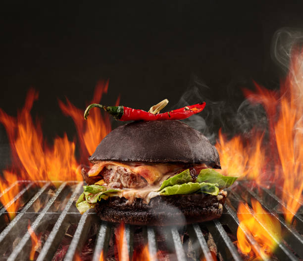 牛肉、レタス、チーズ、赤唐辛子のハンバーガーは、炎の火と残り火の炭で金属ポータブル夏のバーベキューグリルでロースト。クローズアップ - close up roasted meal pepper ストックフォトと画像