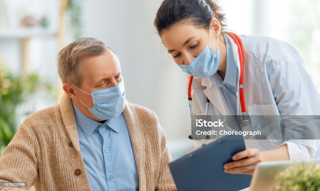 Doctor and senior couple wearing facemasks Doctor and senior man wearing facemasks during coronavirus and flu outbreak. Virus and illness protection, home quarantine. COVID-2019 Patient Stock Photo