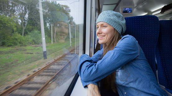 beautiful girl traveling by train and using phone looking out of window