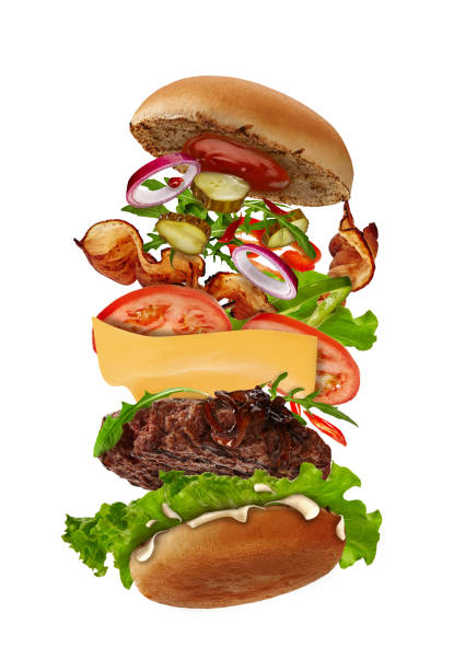 istock Big burger with flying ingredients isolated on white. Ham, beef cutlet, cheese, mayonnaise, ketchup, vegetables and greens. Close up, copy space 1270033140