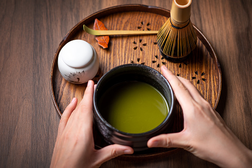 Woman making matcha green tea with traditional accessories for tea ceremony
