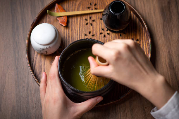 istock Woman whisking matcha powder while making matcha green tea with traditional accessories for tea ceremony 1270033574