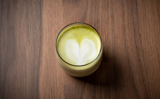 Matcha latte drink with heart shaped latte art on a table top view