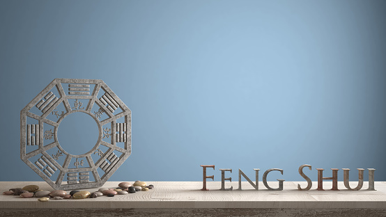 Wooden vintage table shelf with ba gua and 3d letters making the word feng shui with blue navy background with copy space, zen concept interior design