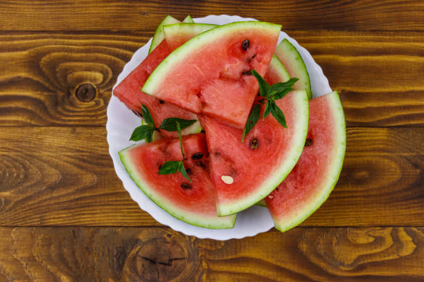 istock Fresh ripe sliced watermelon in white plate on a wooden table. Top view 1270036002