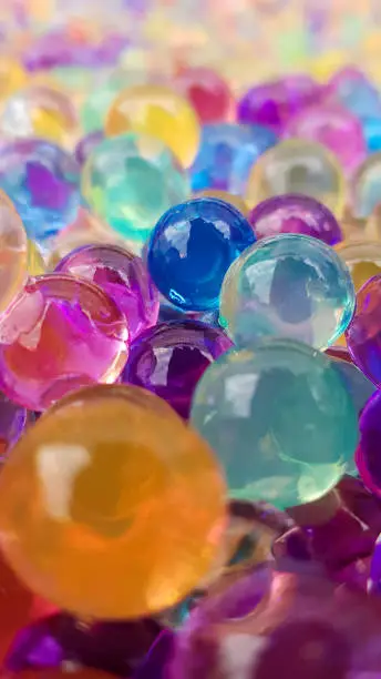 Lots of different colored hydrogel balls. Set of multicolored orbis. Crystal water beads for games. Helium balloons. Can be used as a background. Polymer gel Silica gel
