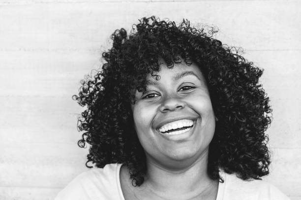 happy black girl laughingoutdoor - young curvy african female having fun smiling on camera - lifestyle concept - focus on face - black and white editing - black and white portrait people women imagens e fotografias de stock