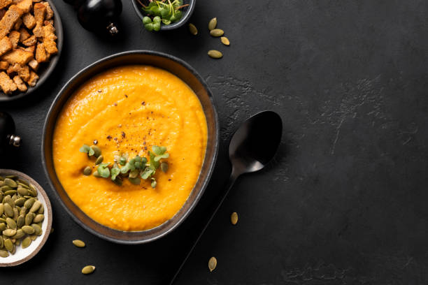 istock Fall pumpkin soup garnish microgreens with ingredients on black background. 1270040392