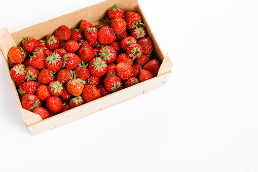 Fresh strawberries in a wooden box on a white background
