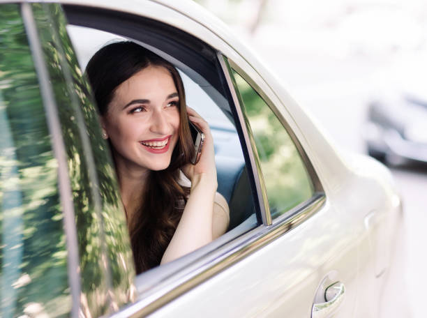 молодая девушка сидит на заднем сиденье автомобиля и разговаривает по телефону - luxury car women smart phone стоковые фото и изображения