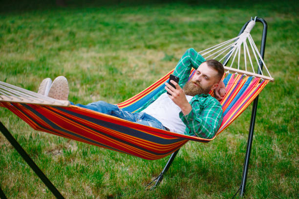 istock man using an app on his mobile phone white swinging in a hammock. 1270043958