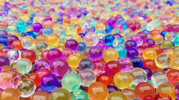 Photo of Lots of different colored hydrogel balls. Set of multicolored orbis. Crystal water beads for games. Helium balloons. Can be used as a background. Polymer gel Silica gel