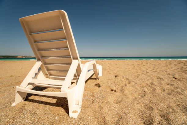 Sunbed are sitting on sands of an empty beach. Easy to crop for all your design and social media needs.