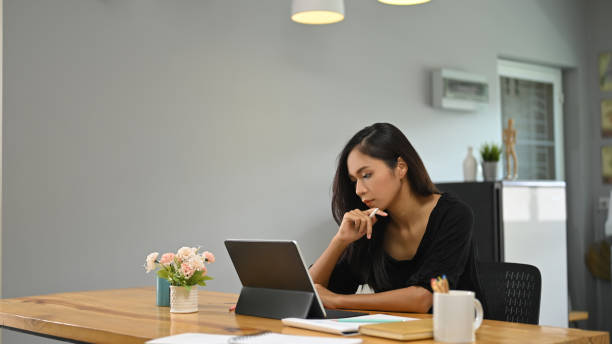 istock A young woman is using a computer tablet while sitting at a wooden table. 1270052280