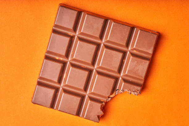 istock Bitten bar of milk chocolate on a colored paper background 1270053575