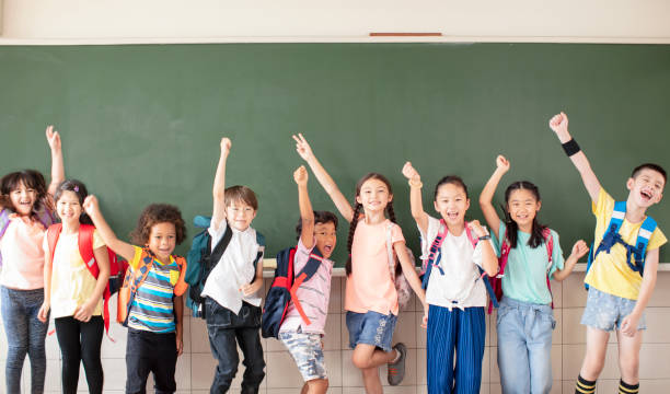 Group of diverse young students standing together in classroom Group of diverse young students standing together in classroom elementary student stock pictures, royalty-free photos & images