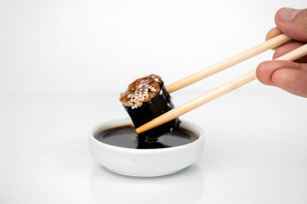 istock take an unagi maki rolls with bamboo chopsticks and put it into soy sauce on white background, asian food, japanese cuisine 1270056942