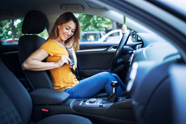 la seguridad primero. hermosa conductora ponerse el cinturón de seguridad antes de conducir un coche. - car safety fotografías e imágenes de stock