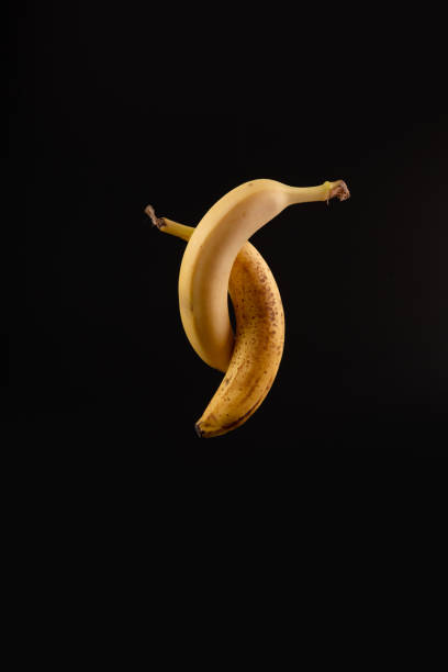 Elegant dancing isolated bananas behind black paper background