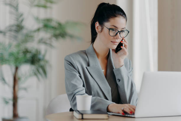 istock Serious brunette woman keyboards information, concentrated into laptop computer, dressed in formal outfit, poses at coworking space, works remotely, involved in working process during daytime. 1270062882