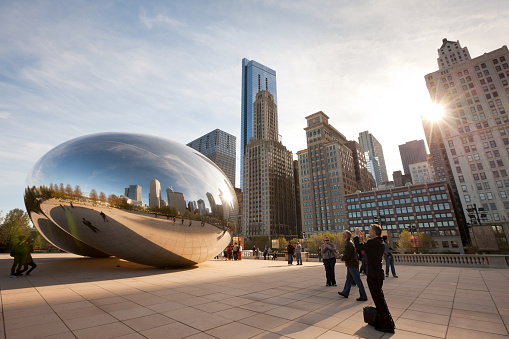 Chicago, Illinois, United States - May 04, 2011: Skyline of buildings and tourists at Millennium Park at downtown visiting Cloud Gate, a sculpture by artist Anish Kapoor..
