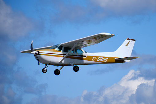 Ottawa, Canada. August 30, 2020. White and brown Cessna 172M Skyhawk plane in flight after taking off from Rockcliffe airport in Ottawa