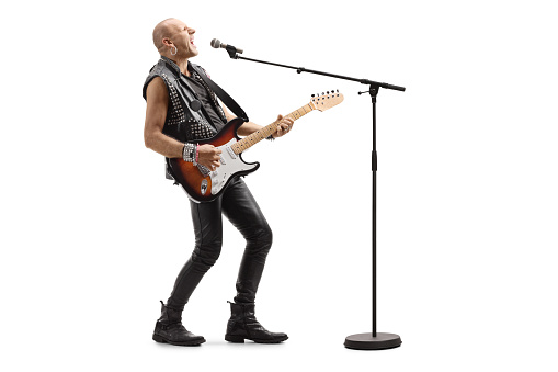 Bald punk rocker singing on a microphone and playing a guitar isolated on white background